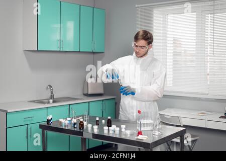 Un jeune scientifique travaillant avec des matériaux liquides dans des tubes à essai en laboratoire. Banque D'Images