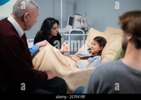 Une famille consolant une petite fille lors de sa visite à l'hôpital. Banque D'Images