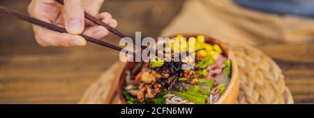 Mangeant un bol de poke avec des crevettes, du maïs, de l'avocat, du gingembre et DES champignons, BANNIÈRE, FORMAT LONG Banque D'Images