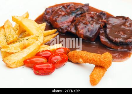 Côtes de porc et doigts de poulet avec sauce barbecue et un côté frites et tomates cerises (sélection) Banque D'Images