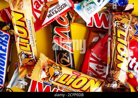 Ukraine, Kiev - 23 mars 2020 : un bouquet de barres de chocolat, dont des Snickers, Twix, Milka, KitKat, Lion, M&M, Bounty, sur fond jaune. Banque D'Images