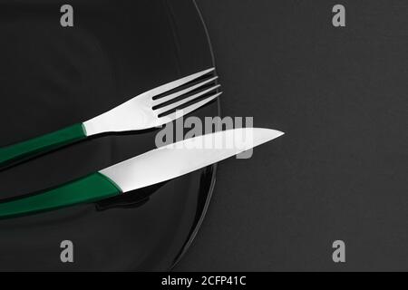 Vider l'assiette en ardoise noire, les couverts sur la table et la serviette en pierre sombre. Fond de nourriture pour le menu, recette. Réglage de la barre de coupe. Mise à plat, vue de dessus. Maquette pour restau Banque D'Images