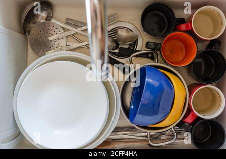 Vaisselle sale dans un évier de cuisine en céramique. Assiettes, tasses et couverts non lavés. Vue de dessus. Gros plan Banque D'Images