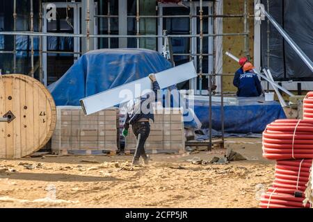 Moscou. Russie. 06 septembre 2020 les travailleurs de la construction qui travaillent dans les uniformes et les casques de sécurité sur le chantier transfèrent manuellement la construction Banque D'Images