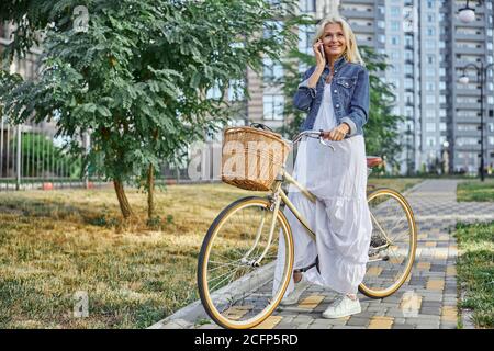 Femme adulte tendance en veste en denim qui arrête de monter à vélo Banque D'Images