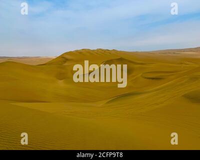 Dunes de sable jaune dans le désert péruvien Atacama près de l'oasis Huacahina. Paysage de sable incroyable. Vue panoramique sur les hautes vagues de sable orange. Mirage du désert. Banque D'Images