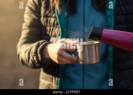 Récolte de femme versant du thé chaud à partir de thermos dans la forêt Banque D'Images