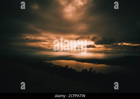 coucher de soleil majestueux dans un ciel orange vif sur une silhouette de montagne. Banque D'Images