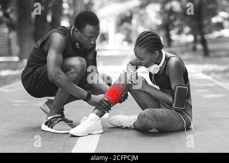 Traumatisme pendant la formation. Femme africaine ayant étendu la cheville après le jogging, BW Shot Banque D'Images