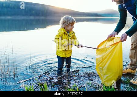 Père avec petit fils collectant des déchets à l'extérieur dans la nature, plugging concept. Banque D'Images