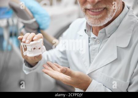 Dentiste âgé montrant un modèle de plâtre de dents Banque D'Images