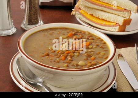 Un bol de soupe de lentilles avec un baloney et du fromage sandwich Banque D'Images