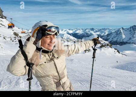 Jeune adulte beau heureux attrayant caucasien souriant skieur femme portrait teke sur le masque sur le pic de la montagne montrant le panorama de la station de ski Banque D'Images