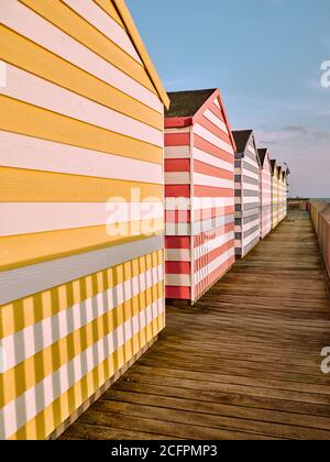 Cabanes de plage d'été à rayures colorées et Hastings Pier à Hastings Sussex Angleterre Royaume-Uni Banque D'Images