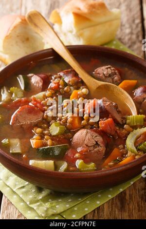 Soupe de lentilles maison avec saucisses et légumes en gros plan dans une assiette sur la table. Verticale Banque D'Images