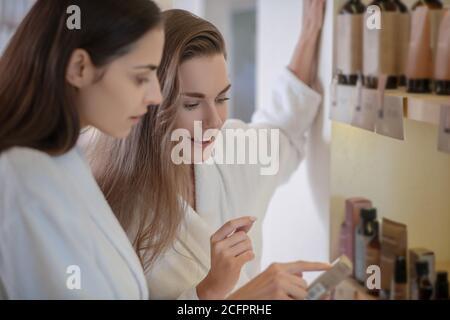 Deux jolies femmes discutant des produits de beauté en salon Banque D'Images