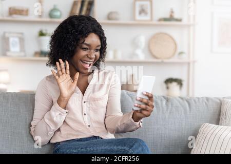 Blog vidéo. Blogger noir Cheeful femelle utilisant un smartphone à la maison, enregistrement de contenu Banque D'Images