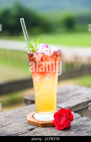 fleurs de thé faites de pétales de rose de thé dans un verre Sur table en bois et fond vert nature / thé glacé Avec une rose de thé cocktail froid Banque D'Images