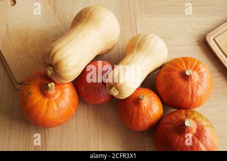 Photo de haut en bas de superbes citrouilles fraîches mûres et planches à découper sur une table en bois brun clair Banque D'Images