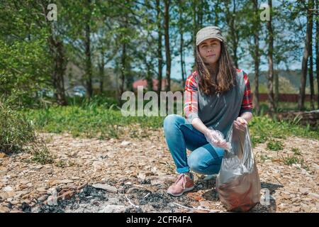 Une jeune femme bénévole collecte les ordures dans l'aire de pique-nique. Le concept du jour de la terre et de l'écologie et de la conservation de l'environnement. Banque D'Images