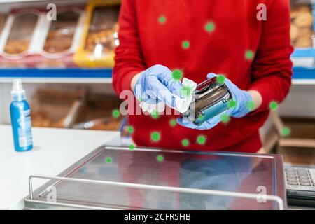 Protection des bactéries. Une femme en gants de caoutchouc traite le terminal avec un antiseptique. En arrière-plan se trouvent les étagères du magasin. Le concept de coron Banque D'Images