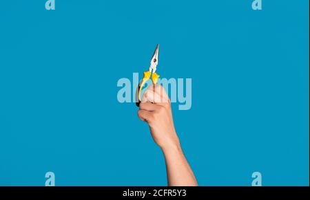 Vue rognée du handyman tenant une pince à bec plat sur fond bleu, gros plan Banque D'Images