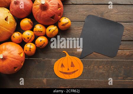 Plan horizontal de citrouilles sculptées, papier de mandarine Jack-O'-Lanterne avec boîte de citation noire sur une table en bois brun foncé Banque D'Images