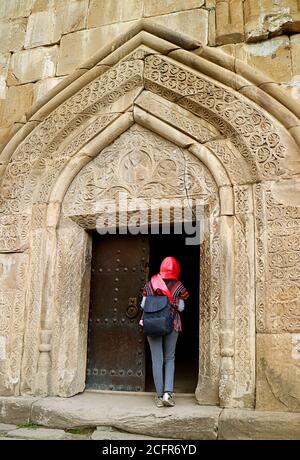 Femme voyageur en tête couvrant à l'entrée de l'église de l'Assomption dans le complexe du château d'Ananuri, Aragvi River Bank, Géorgie Banque D'Images