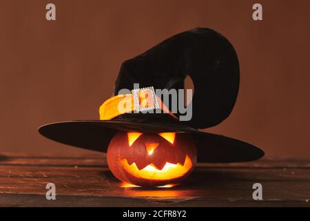 Gros plan studio photo de la jolie Jack O' Lantern portant un chapeau de sorcière noir avec bougie à l'intérieur, fond marron Banque D'Images