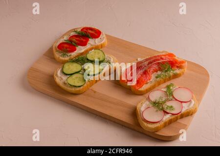 Sandwichs avec morceaux de truite, avocat, radis. Parfait pour le petit déjeuner. Sur un fond blanc et concret. Banque D'Images