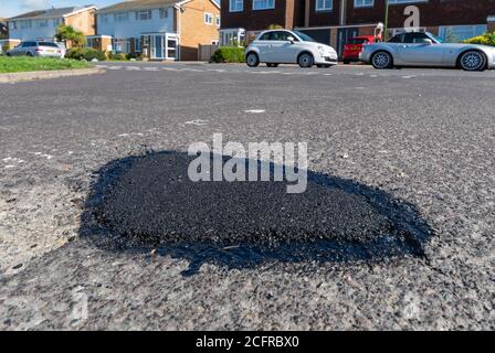 Dans un trou de la route où le tarmac a été utilisé pour réparer un nid-de-poule sur une route asphaltée au Royaume-Uni. Banque D'Images