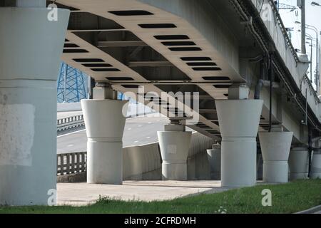 Vue de dessous des piers en béton du viaduc de transport. Des colonnes massives soutiennent le pont routier. Jour ensoleillé. Photo de haute qualité Banque D'Images