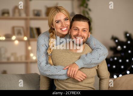 Homme et femme joyeux se câliner à la maison pendant la veille de Noël Banque D'Images