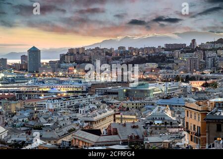Vue sur le toit du Vieux Port, Gênes, Ligurie, Italie au crépuscule avec des bâtiments éclairés en bord de mer dans le port et la ligne d'horizon contre les nuages de coucher de soleil Banque D'Images