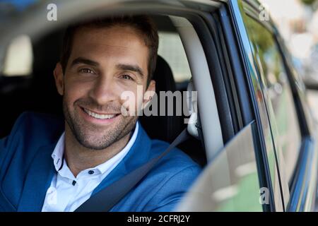 Homme souriant assis dans sa voiture pendant son trajet du matin Banque D'Images
