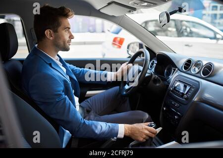 Homme conduisant dans une voiture le long d'une rue dans le ville Banque D'Images