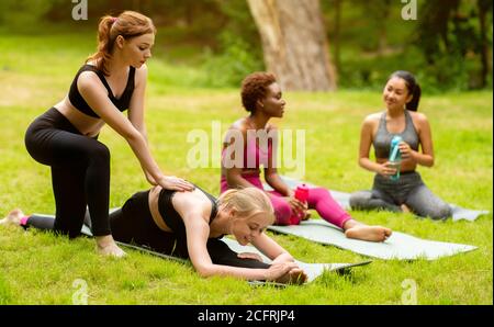 Jeunes filles multinationales pratiquant le yoga avec un entraîneur pendant les cours en plein air au parc Banque D'Images
