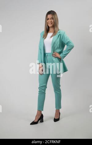 debout élégante jeune femme latine dans un costume léger et chaussures à talons, studio Banque D'Images