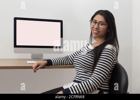 jeune femme latine assise devant un ordinateur dans un bureau, psychologue Banque D'Images