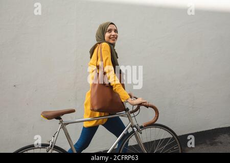 Femme en hijab marchant avec un vélo Banque D'Images
