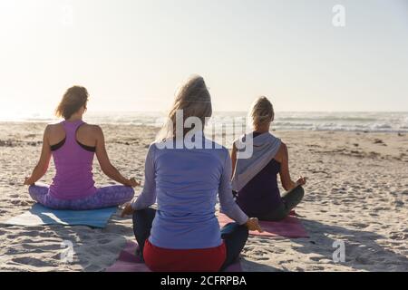 Vue arrière du groupe de femmes pratiquant le yoga sur le plage Banque D'Images