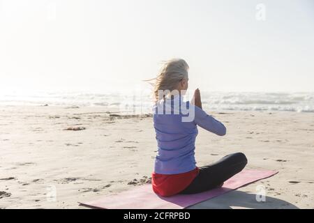 Vue arrière d'une femme pratiquant le yoga sur la plage Banque D'Images