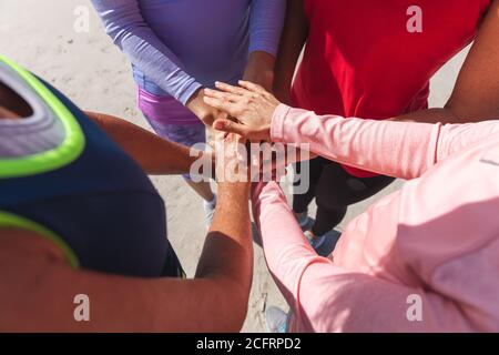 Section médiane du groupe de femmes en empilant les mains ensemble à la plage Banque D'Images