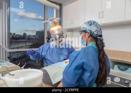 deux dentistes avec masque facial et protections travaillant sur la salle de consultation avec un patient, détails Banque D'Images