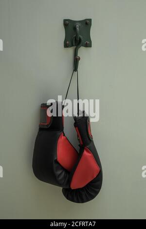 gants de boxe rouge et noir suspendus avec un fond blanc, studio Banque D'Images