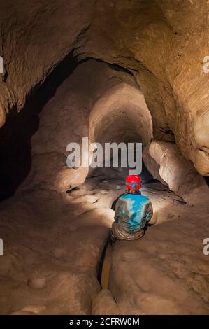 Dominika Wroblewska dans l'approche très boueuse de la chambre de mousse dans la caverne de pic, regardant la pente descendante Banque D'Images