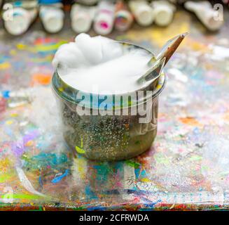 Les brosses de l'artiste dans un contenant d'eau bouillant Banque D'Images