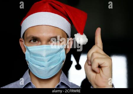 Portrait de l'homme en masque médical et chapeau du Père Noël. Célébration de Noël pendant la pandémie du coronavirus Banque D'Images