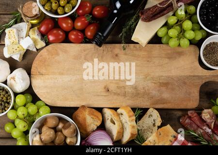 Vue sur une planche à découper en bois avec pain, fromage, saucisse, fruits et vin sur une surface en bois Banque D'Images