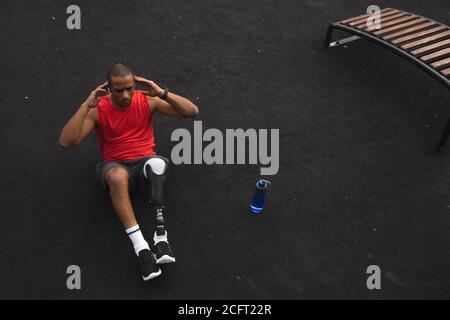 Homme avec une jambe prothétique effectuant un exercice de craquements dans le parc Banque D'Images
